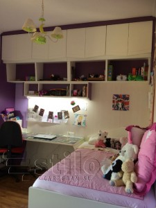 Dormitorio infantil compuesto por un mural con armarios, estantería, mesa de estudio y cama.